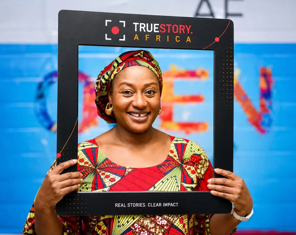 A woman holding a TrueStory Africa branded photo frame at an event