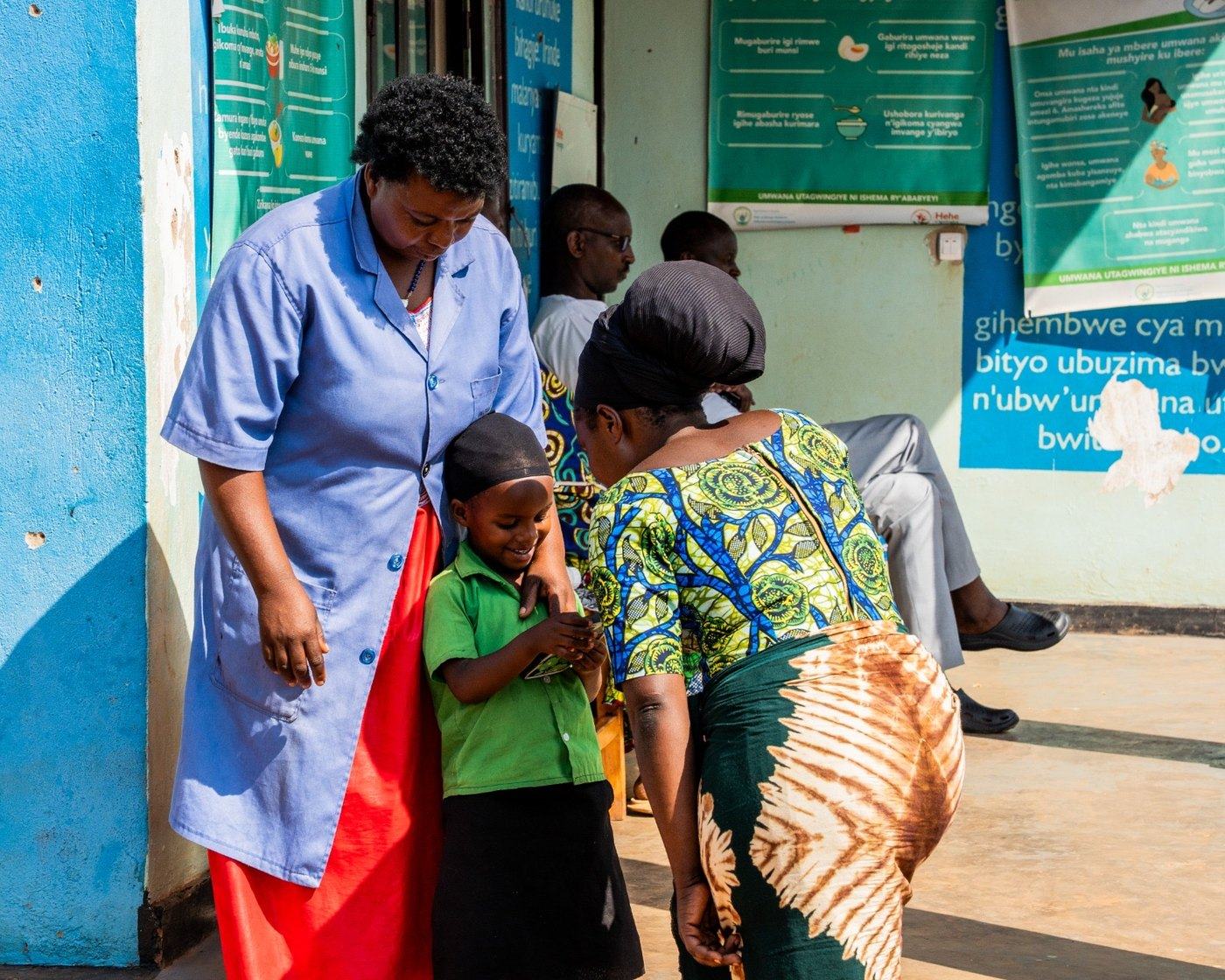 A Community Health Worker with a mother and child at a health post