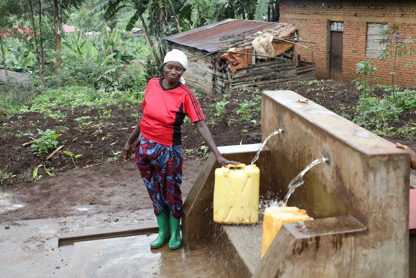 Nyirandorimana Frodinatha fills her jerrycans at the newly rehabilitated water supply in Muko