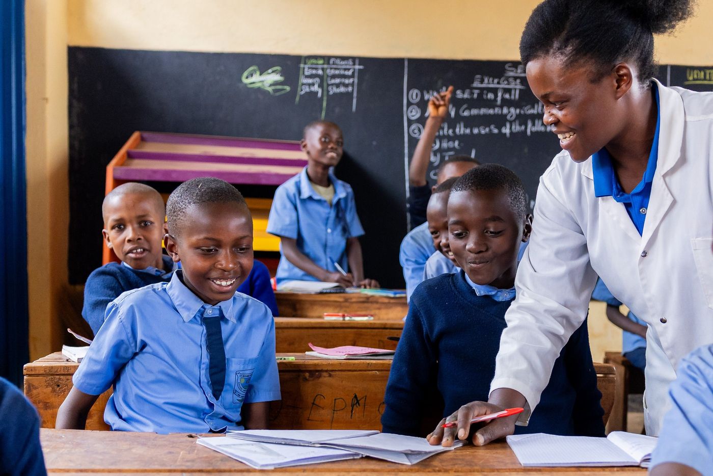 A teacher helps pupils with their work in a classroom in Rwanda